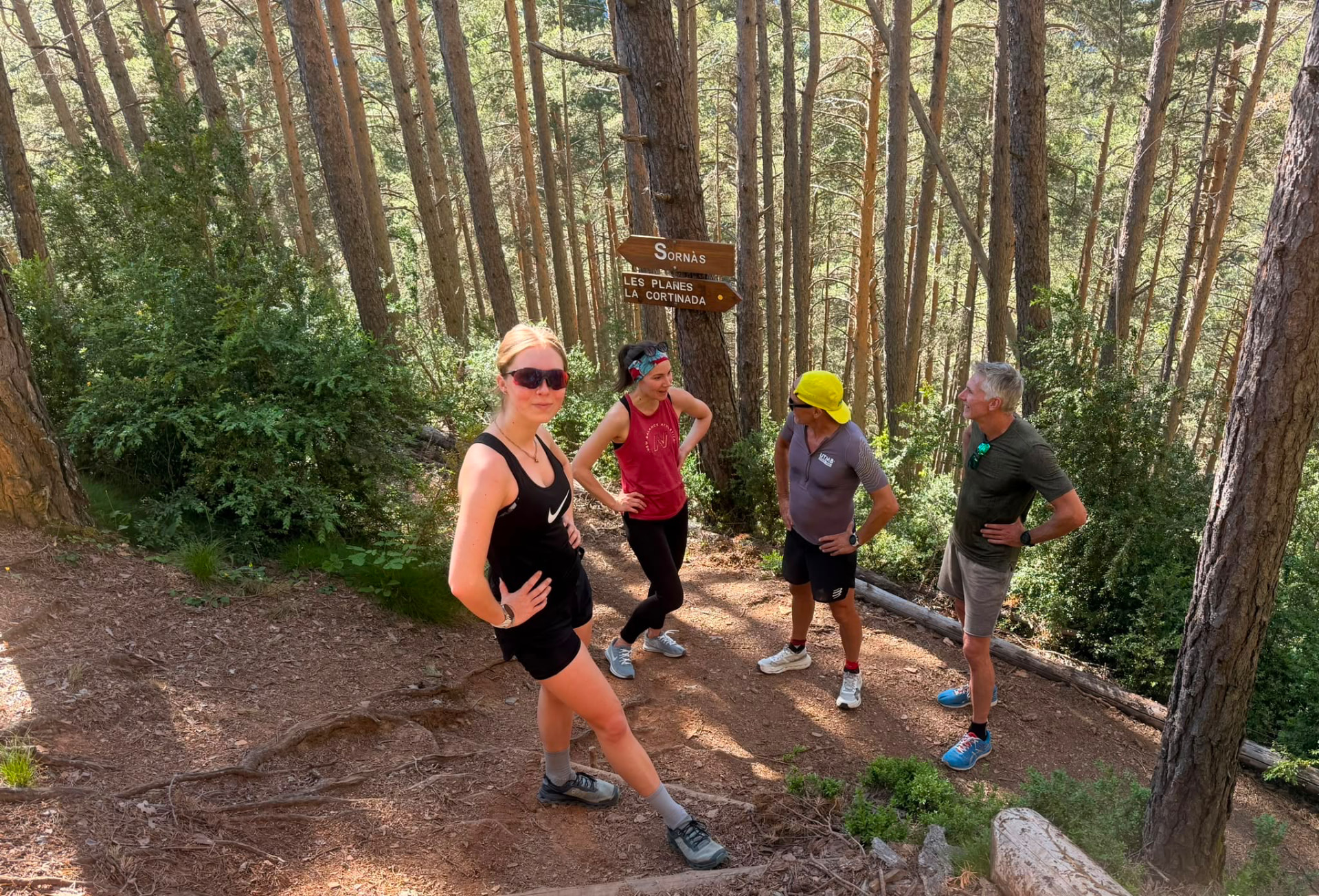 Trail runners at a signpost in the forest above Ordino