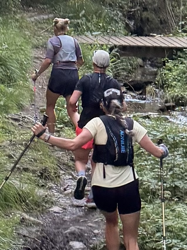 Trail runners climbing a streamside forest path with poles in Andorra