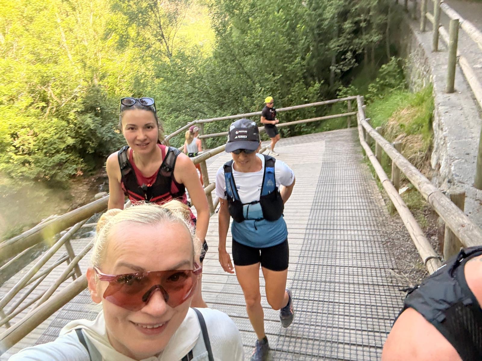 Run the Pyrenees runners crossing a wooden riverside boardwalk in Ordino